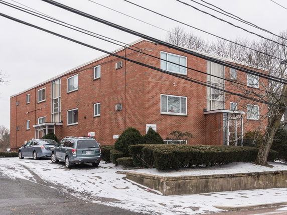 Front view of a three-story brick apartment building with multiple windows.