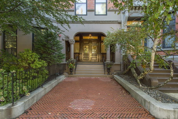 Front view of a traditional multi-story building with steps leading to an arched entrance.