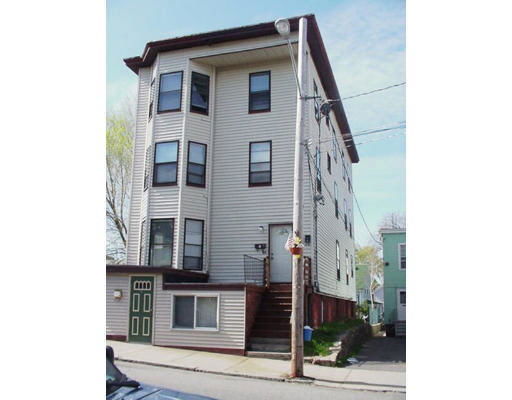 Front view of a multi-story residential building with bay windows and an external staircase.