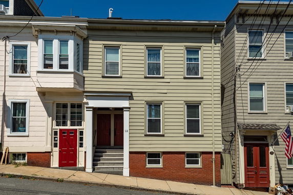 Front view of a multi-story building with a red door and beige siding.