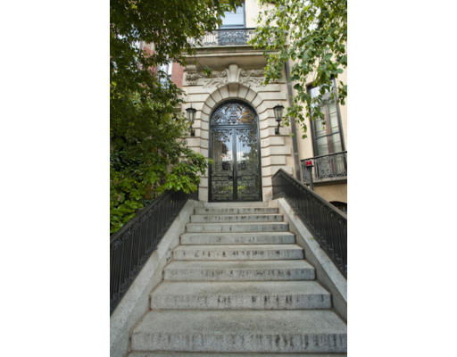 Front view of a building with a staircase leading to an ornate entrance.