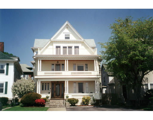 Front view of a multi-story house with a symmetrical facade and two large balconies.