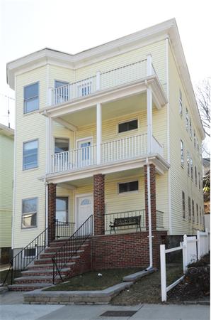 Front view of a multi-story house with multiple balconies and brick steps.
