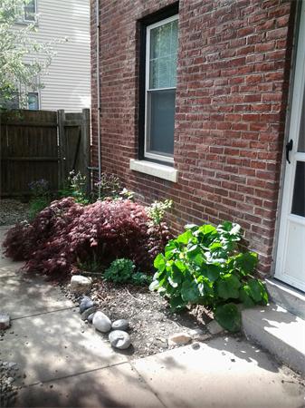 Side view of a brick house with a window and a small garden.