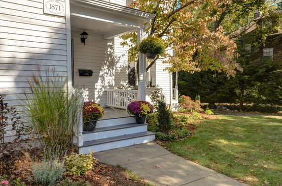 Front view of a house with a porch and steps, surrounded by a garden