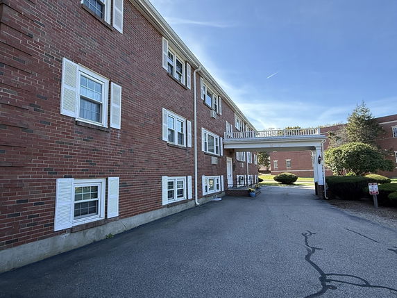 Side view of a multi-story brick building with white window shutters and a connecting walkway.
