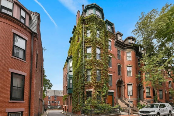 Front view of a multi-story brick building with vines covering part of the facade.
