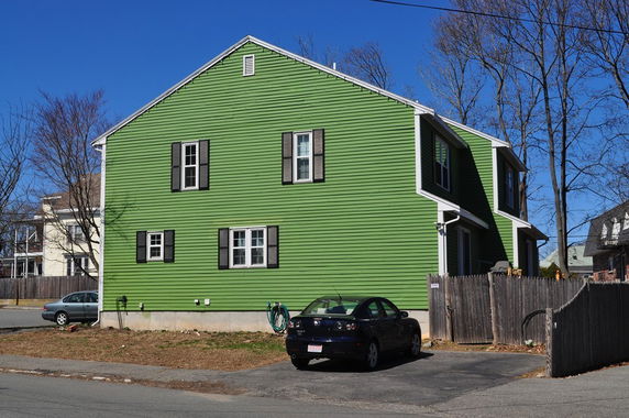 Side view of a green two-story house with black shutters.