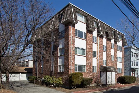 Front view of a multi-story brick apartment building with a pitched roof.