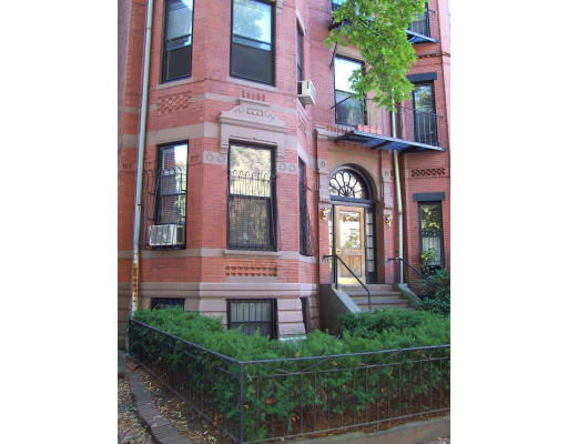 Front view of a multi-story brick building with large windows and an arched doorway.