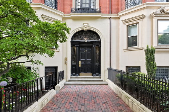 Front view of a multi-story townhome with an ornate black door and brick facade.