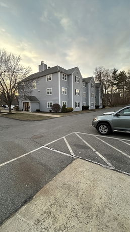 Front view of a multi-story apartment building with gray siding and multiple windows.