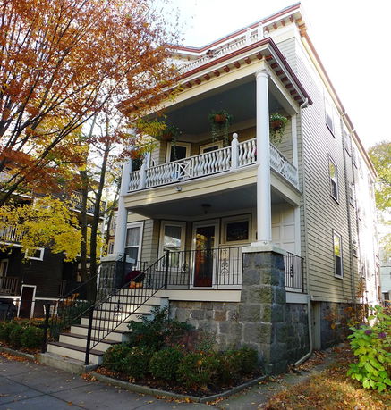 Front view of a three-story house with balcony and staircase.