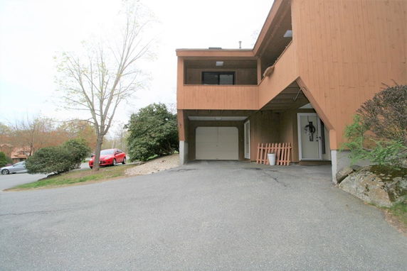 Front view of a house with an attached elevated structure and driveway.