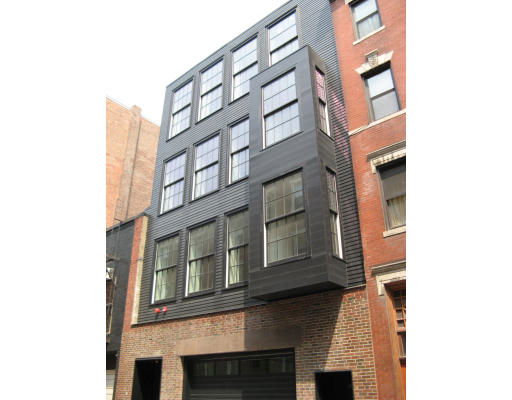 Front view of a modern multi-story building with large windows and a garage door.