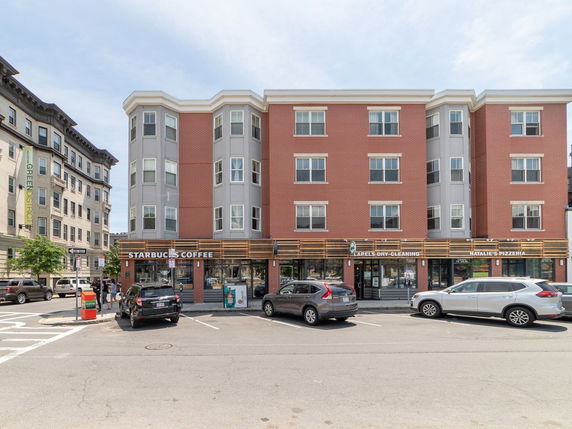 Front view of a multi-story building with red brick facade, hosting various shops including Starbucks Coffee.