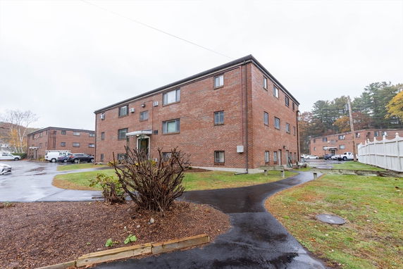 Front view of a two-story brick apartment building with parking area.