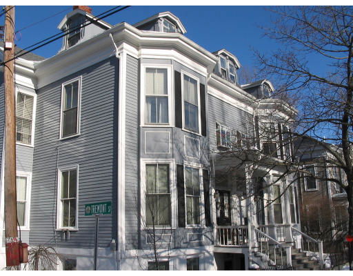 Front view of a multi-story residential building with bay windows and dormer windows on the roof.