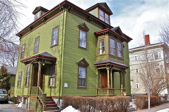 Front view of a two-story house with green exterior and multiple windows.
