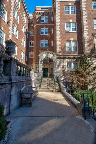 Front view of a multi-story brick building with an arched entryway and steps leading to the entrance.