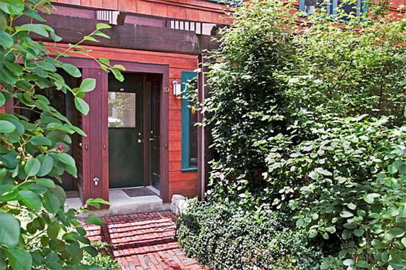 Front view of a brick-faced house entrance with surrounding greenery.