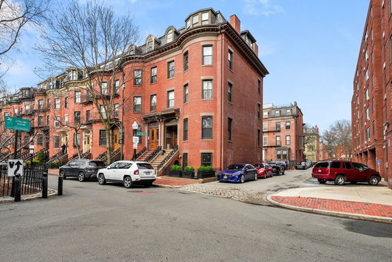 Front view of a row of multi-story brick townhouses on a street corner.