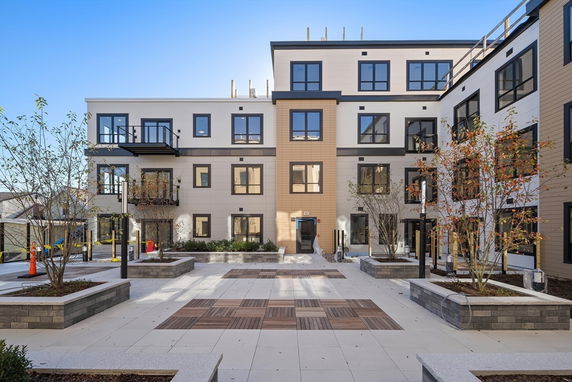 Front view of a multi-story apartment building with a central courtyard.
