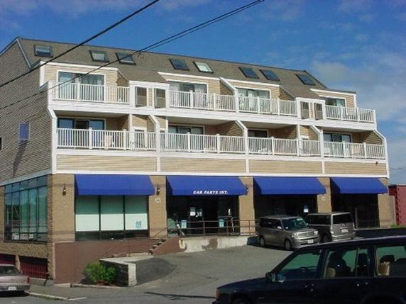 Front view of a multi-story commercial building with blue awnings and balconies.