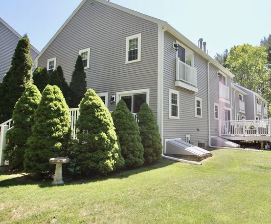 Side view of a multi-story house with gray siding and balconies.