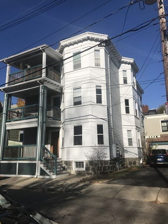 Front view of a three-story house with balconies and a stone foundation.