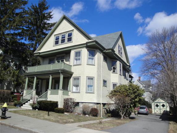 Front view of a three-story house with a porch and gabled roof.