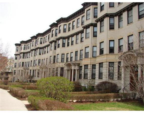 Front view of a multi-story residential building with numerous windows and a classical architectural style.