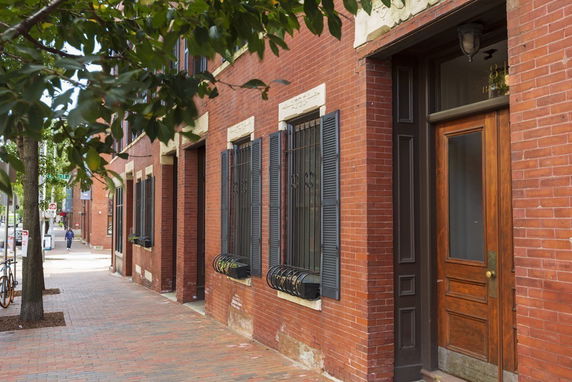 Front view of a multi-story brick building with wooden doors and shuttered windows.