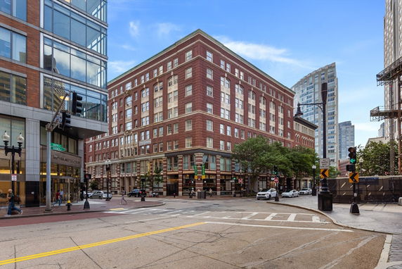 Front view of a large multi-story brick building at a city intersection.