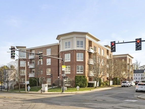 Front view of a multi-story brick apartment building at a street intersection.