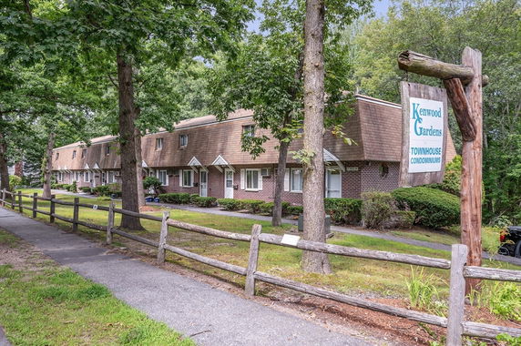 Front view of a row of townhouse condominiums with a sign reading 'Kenwood Gardens.'