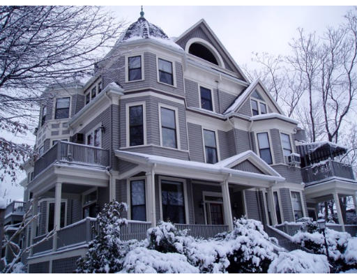 Front view of a multi-story house with a turret and multiple dormer windows, covered in snow.