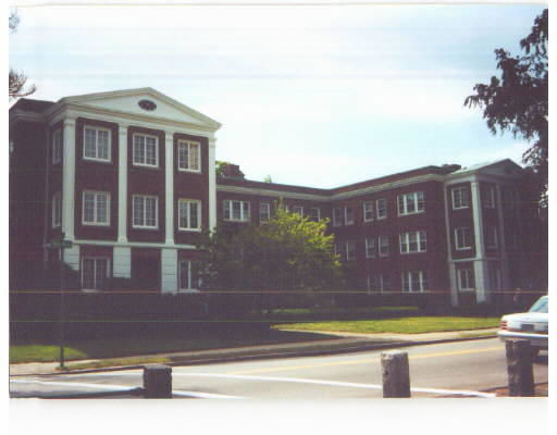 Front view of a large, three-story brick building with white accents and numerous windows.
