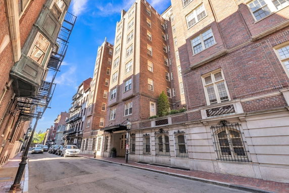 Front view of a multi-story brick building with fire escapes and large windows.
