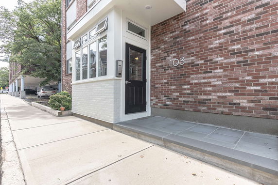 Front view of a brick building entrance with the number 103 displayed.
