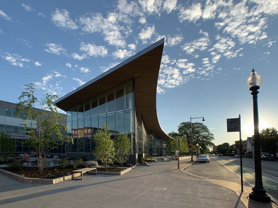 Front view of a modern building with a unique sloped roof and large glass windows.