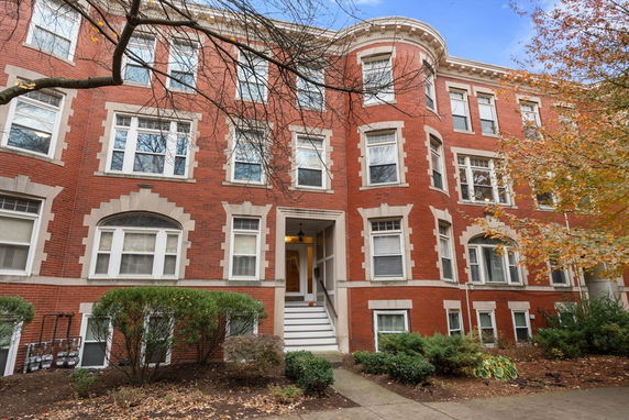 Front view of a multi-story brick building with multiple windows and a central entrance.