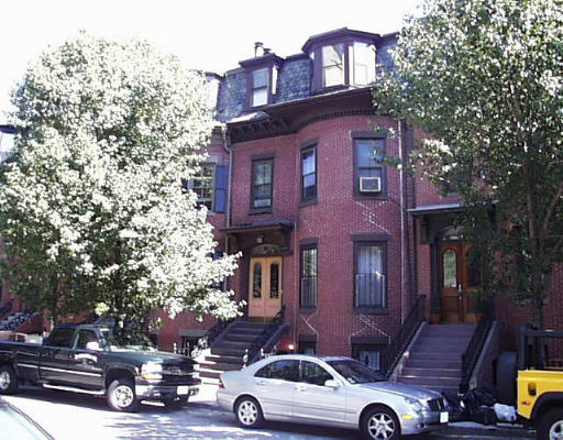 Front view of a multi-story brick townhouse with steps leading to the entrance.