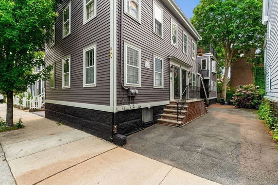 Front view of a multi-story house with a brick staircase and siding exterior.