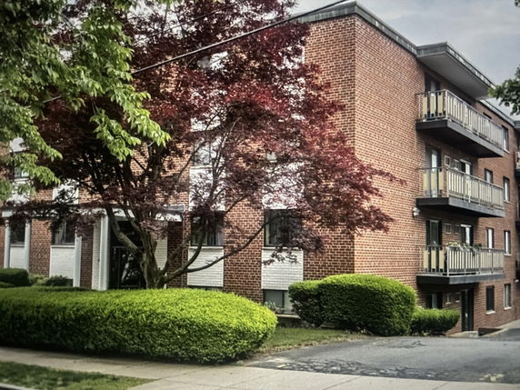 Front view of a brick apartment building with balconies.