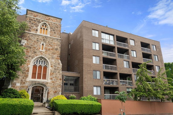 Front view of a multi-story brick building with a historic stone facade and glass entrance.