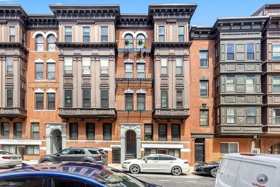 Front view of a multi-story brick building with large windows and decorative elements.