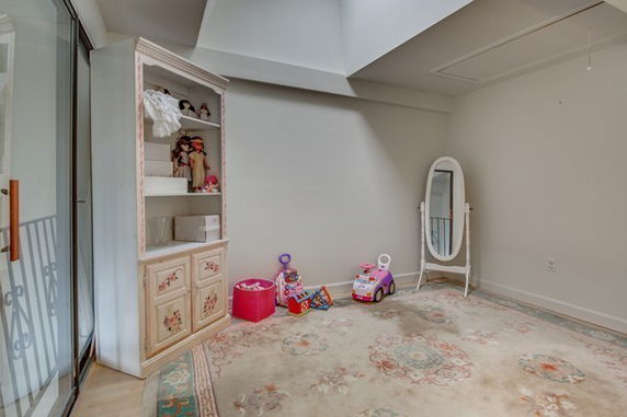 A small indoor play area with a shelf containing toys and a large mirror.