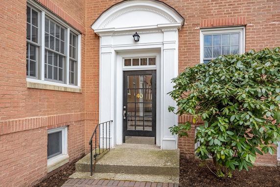 Front view of a brick building entrance with decorative arch and glass door.