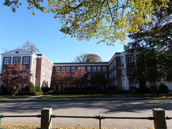 Front view of a multi-story brick building with white trim and large windows.
